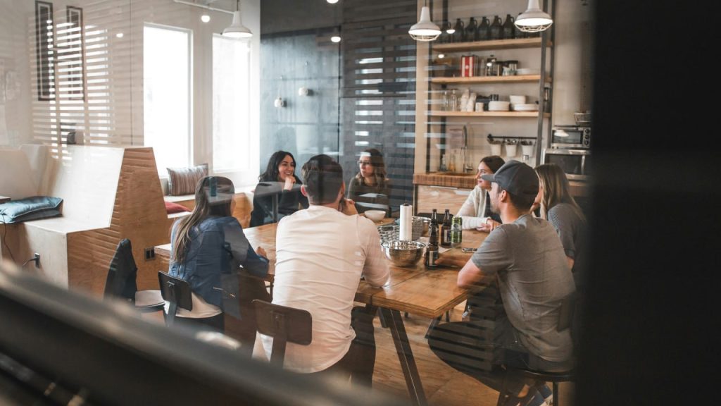 Eigentümerversammlung – Wohnungseigentümer sitzen gemeinsam am Tisch und besprechen Entscheidungen